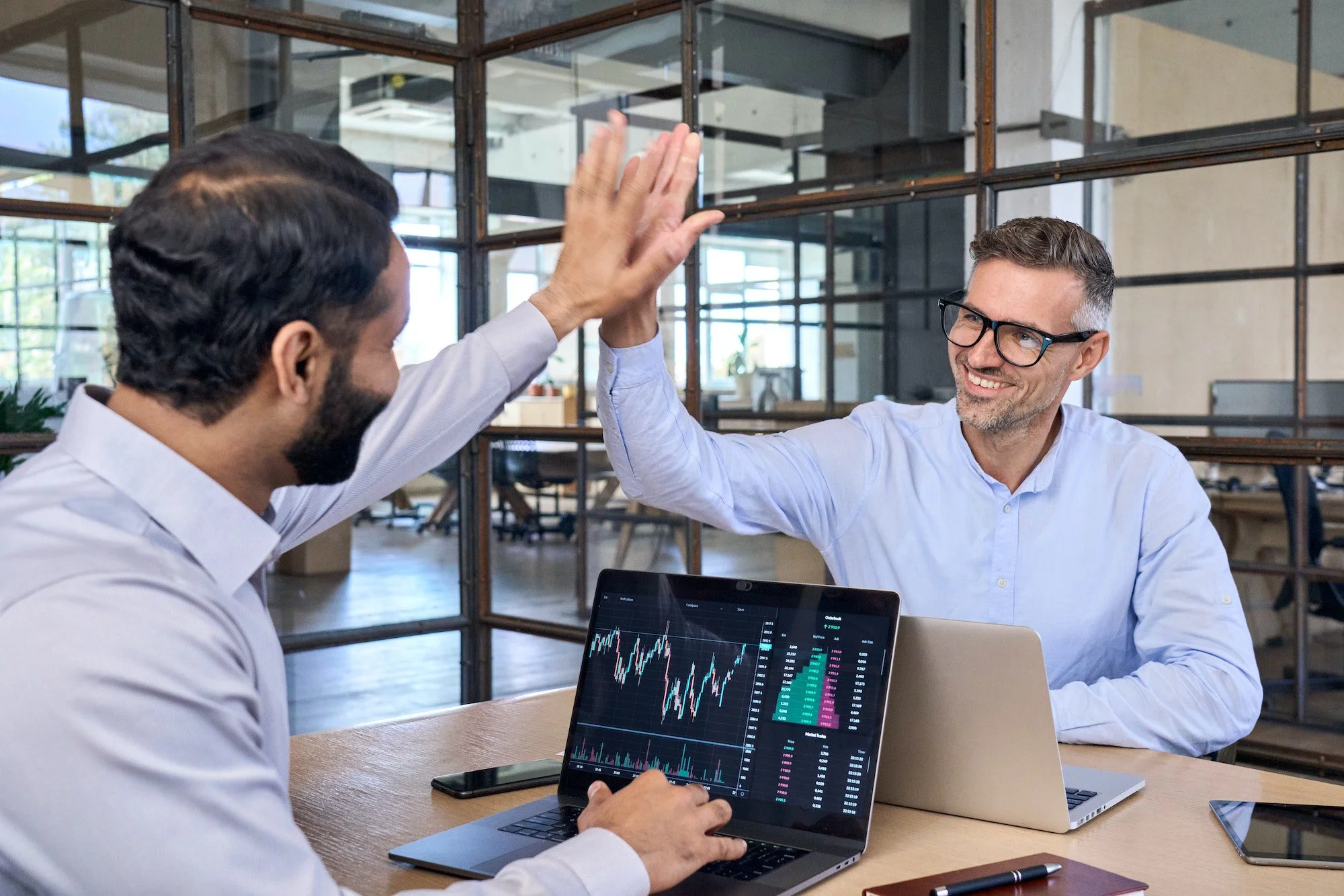 Two happy successful diverse traders investors giving high five.